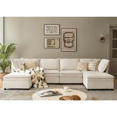 a living room with white furniture and pictures on the wall above it's couch