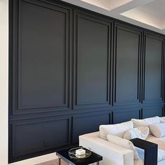 a living room filled with white furniture and black walls