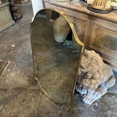 a mirror sitting on top of a floor next to a vase and other items in a room