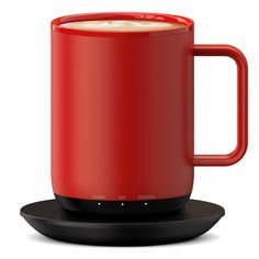 a red coffee mug sitting on top of a saucer next to a black plate