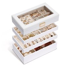 three white boxes filled with jewelry on top of each other