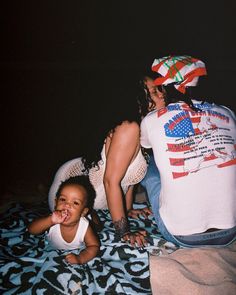 a woman and child sitting on a bed with an american flag t - shirt over them