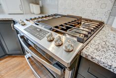 Kitchen remodel with white upper cabinets, a grey backsplash, light granite countertops, new vinyl plank flooring, and farm sink under the bay window Washing Dishes