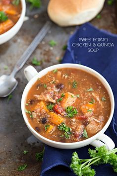 a white bowl filled with meat and vegetable soup on top of a blue cloth next to a spoon