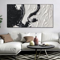 a living room with a white couch and black and white painting on the wall