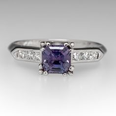 This gorgeous blue to purple color change sapphire engagement ring features a 1.16 carat no heat sapphire with Montana, USA origin that we sourced and set in a vintage platinum diamond mounting. The shoulders of the ring are each accented with three (3), channel set, round single cut diamonds, bordered with milgrain edging. The ring measures 6.2mm at the top, rises 6.3mm above the finger, tapering to 1.5mm wide and 1.3mm thick at the base of the shank. The ring is currently a size 5.75 and we offer complimentary resizing to fit. Classic Sapphire Rings In Purple, Classic Purple Sapphire Ring For Wedding, Classic Purple Sapphire Wedding Ring, Classic Purple Sapphire Ring With Prong Setting, Classic Purple Sapphire Promise Ring, Purple Sapphire Ring With Brilliant Cut For Anniversary, Montana Sapphire Engagement, Montana Sapphire Engagement Ring, Color Change Sapphire