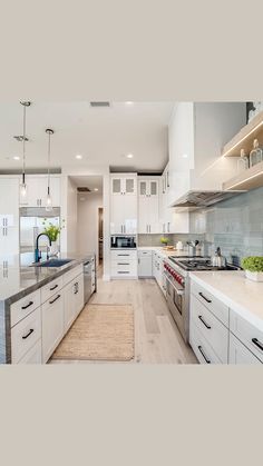 a large kitchen with white cabinets and stainless steel appliances, along with an island in the middle