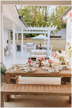 a wooden table with plates and cups on it in front of an outdoor dining area