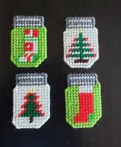 four cross stitch christmas coasters on a table with one decorated in red, white and green