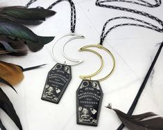 Add a touch of spooky playfulness with this Moon Coffin Necklace. Featuring a long black figaro chain that holds a gold crescent moon and a resin coffin that has a Ouija board printed on both sides. This is the perfect mix of witchy and magical. NECKLACE LENGTH: 32inches (Approx 81cm) MATERIAL: Brass Coated Iron Chain, Gold Plated Alloy Moon, Resin Coffin Pendant COLOR: Black and Gold QUANTITY: 1 Necklace For more HALLOWEEN designs, CLICK HERE! https://www.etsy.com/shop/SpotLightJewelry?ref=seller-platform-mcnav&search_query=Halloween For more GOTHIC designs, CLICK HERE! https://www.etsy.com/shop/SpotLightJewelry?ref=seller-platform-mcnav&search_query=Gothic THANK YOU FOR CHOOSING SPOTLIGHT JEWELRY! Our mission is to put a SpotLight on Women and their unlimited potential. At Spotlight Jewe Gold Metal Necklace For Halloween, Spooky Black Necklace For Gift, Gold Necklace With Adjustable Chain For Halloween, Black Halloween Jewelry With Charms, Halloween Black Jewelry With Charms, Halloween Moon Charm Jewelry As Gift, Black Moon Charm Jewelry For Halloween, Black Halloween Moon Charm Jewelry, Spooky Black Jewelry Gift