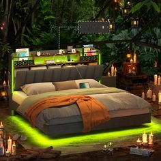 a large bed with lots of candles on the floor next to trees and lights around it