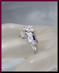 a diamond and blue sapphire ring sitting on top of a white glove