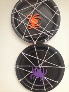 two paper plates decorated with spider webs and purple, orange and black decorations on them