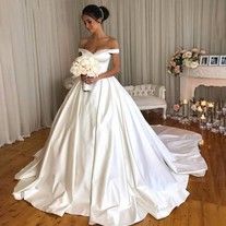 a woman in a white wedding dress standing on a wooden floor next to a fireplace