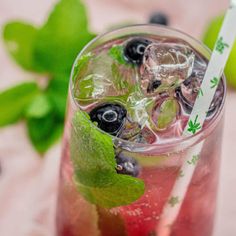 a close up of a drink in a glass with ice and berries on the rim