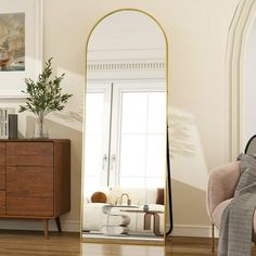 a large mirror sitting on top of a wooden floor next to a dresser and chair