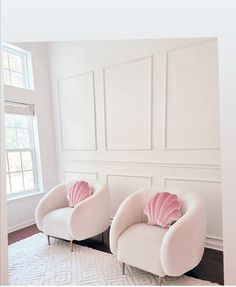 two white chairs with pink pillows on them