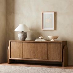 a table with a lamp and vase on it next to a wall in a living room