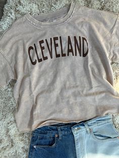 Cleveland Vintage wash, boxy tee. Oversized crop top (moderate length top) distressed hem, Brown Cleveland print detailing Faded Washed Sporty Top, Faded Sporty Top, Sporty Acid Wash Soft-washed Tops, Sporty Acid Wash Distressed Top, Trendy Bleached Tops For Streetwear, Acid Wash Sporty Top With Letter Print, Sporty Acid Wash Top With Letter Print, Casual Cropped T-shirt With Letter Print For College, Casual Crew Neck Soft-washed Crop Top