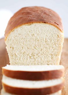 a loaf of white bread sitting on top of a cutting board next to slices of bread