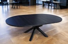 a black table sitting on top of a wooden floor next to chairs and dining tables