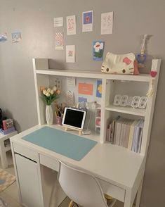 a white desk with a computer on it in front of a bookshelf and shelves