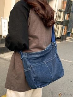 a woman is walking down the street carrying a blue handbag on her back,