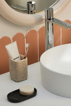 a bathroom sink with soap, toothpaste and brush holder on the counter next to it