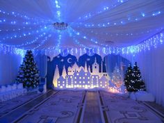 a room decorated for christmas with blue lights and white drapes on the ceiling is lit up