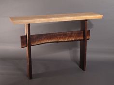 a wooden table sitting on top of a gray wall next to a shelf with two shelves