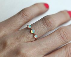 a woman's hand wearing a ring with three opals on the middle of it