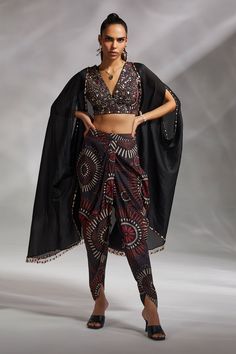 Black crushed organza oversized cape with embroidery and tassel details. Comes with padded blouse and printed dhoti pant.
Component: 3
Pattern: Print and Embroidery
Type Of Work: Geometric Print and Bead, Tassel Embroidery
Neckline: Blouse: V Neck, Cape: Open
Sleeve Type: Blouse: Sleeveless, Cape: Split
Fabric: Cape: Crushed Organza, Blouse and Dhoti Pant: Silk Dupion
Color: Black
Other Details: 
Attached lining
Approx weight (in kg) : 800 gms
Note: The neckpiece worn by the model is not for sal