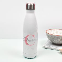 a white bottle next to a bowl and spoon on a marble counter top with the name clarice written on it