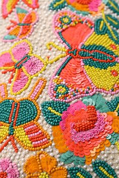 closeup of colorful beaded fabric with flowers and leaves on white background, detail view