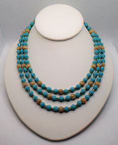 "Vintage Textured Gold Tone Beads and Aqua Blue Faux Turquoise Faceted Beads Triple Strand Necklace. The necklace is marked Trifari with the crown over the T and also has the metal Crown over T hang tag. The Set was part of their \"Electra\" collection circa 1962. The necklace has a hook closure for adjustability. The small gold tone bead spacers have some discoloring from age closer to the back of the necklace as well as the strand connectors and hook. Be sure to check out all the pictures for Vintage Beaded Turquoise Necklace With Round Beads, Turquoise Faceted Beads Costume Jewelry Necklace, Turquoise Faceted Beads Costume Necklace, Turquoise Faceted Beaded Costume Jewelry Necklace, Vintage Turquoise Jewelry With Colorful Beads, Turquoise Faceted Beads Costume Jewelry, Vintage Blue Beaded Turquoise Necklace, Beaded Blue Turquoise Costume Jewelry Necklace, Beaded Blue Turquoise Costume Necklace