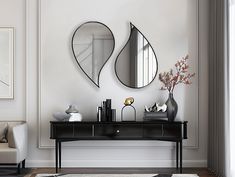 two mirrors are hanging on the wall above a black table with vases and flowers