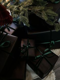 presents wrapped in brown paper and tied with green ribbon are sitting on a table next to a christmas tree