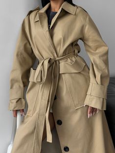 "Beige trench coat under the belt with large front patch pockets is stylish and elegant!  Our straight collar raincoat with epaulettes is made from thick cotton and fastens with buttons at the front.  The raincoat goes well with various styles of clothing and shoes and is suitable for both a casual look for every day and for special occasions.    DETAILS  - beige  - 100% cotton  - oversized  - straight collar  - buttoned  - large front patch pockets  - epaulettes  SIZES  This trench coat is avai Winter Workwear Raincoat, Single-breasted, Winter Workwear Raincoat Single Breasted, Belted Solid Outerwear For Work, Winter Single-breasted Raincoat For Work, Belted Solid Workwear Outerwear, Belted Gabardine Outerwear For Work, Solid Outerwear With Belted Cuffs For Work, Khaki Long Coat With Hidden Button Closure, Khaki Long Coat For Office