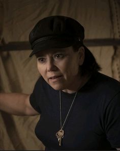 a woman wearing a black hat with a gold key on it's neck and a chain around her neck