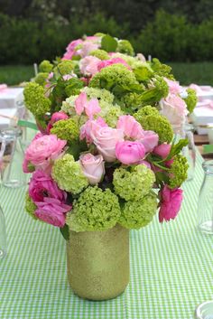 a vase filled with pink and green flowers on top of a table