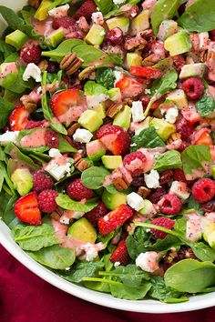 a white bowl filled with spinach, strawberries and feta cheese