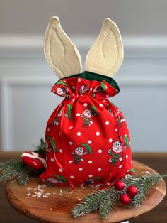 a red bag with white ears on top of a wooden table next to christmas decorations