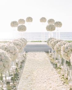 the aisle is lined with white flowers and candles for an outdoor ceremony at the beach