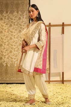 Ivory short kurta with placement floral embroidery using gota patti, dabka, zardozi work. Paired with a salwar with embroidered hem and dupatta with all over geometric pattern and embroidered border. - Aza Fashions Off White Raw Silk Designer Wear Sets, Off White Raw Silk Designer Sets, Off White Raw Silk Sets For Designer Wear, Off White Raw Silk Sets With Traditional Drape, Designer Cream Sets With Traditional Drape, Cream Traditional Drape Sets With Zari Work, Off White Raw Silk Sets With Dupatta, Cream Zari Work Sets, Traditional Beige Sets With Traditional Drape