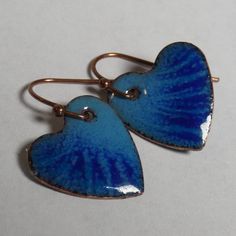 two blue heart shaped earrings sitting on top of each other