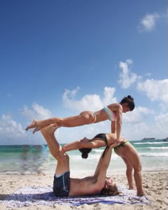 two women are doing acrobatic on the beach while another woman is holding her