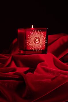 a lit candle sitting on top of a red blanket