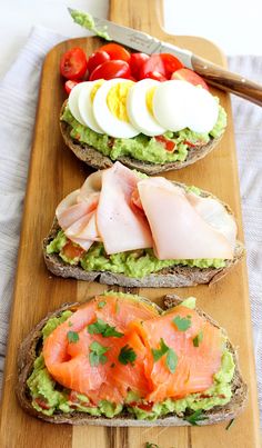 three slices of bread with avocado, salmon and hard boiled eggs on them