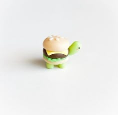 a small toy turtle with a hamburger on it's back, sitting in front of a white background