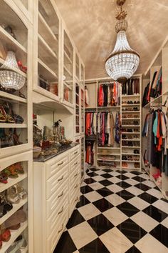 a walk - in closet with black and white checkered flooring, chandelier hanging from the ceiling